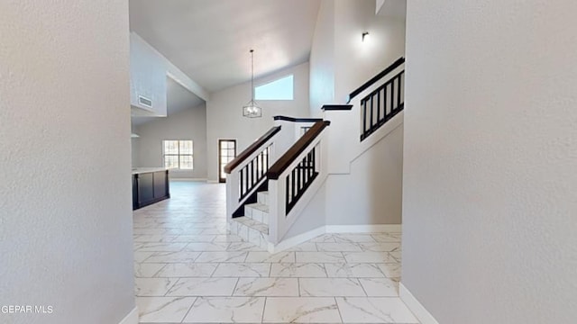 staircase featuring a chandelier and high vaulted ceiling