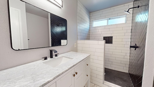 bathroom with tiled shower and vanity