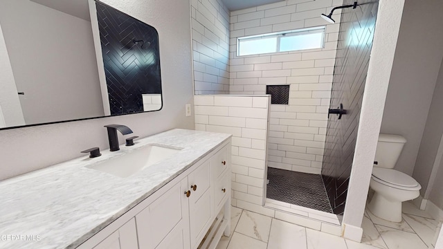 bathroom featuring a tile shower, vanity, and toilet