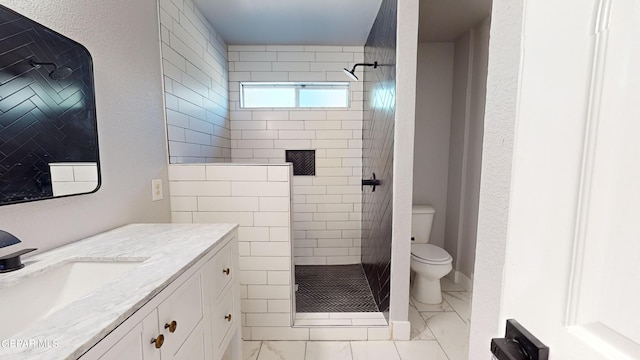 bathroom with a tile shower, vanity, and toilet