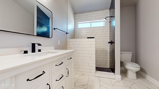 bathroom with a tile shower, vanity, and toilet