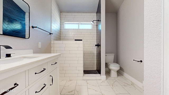 bathroom featuring a tile shower, vanity, and toilet