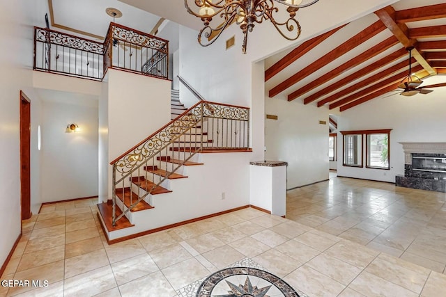 staircase with tile patterned floors, beam ceiling, a premium fireplace, high vaulted ceiling, and ceiling fan with notable chandelier