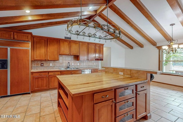 kitchen featuring paneled fridge, a kitchen island, butcher block counters, sink, and decorative light fixtures