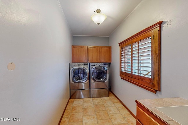 clothes washing area featuring crown molding, washing machine and dryer, and cabinets