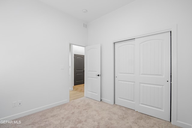 unfurnished bedroom featuring a closet and light colored carpet