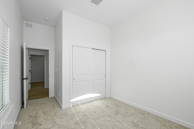 unfurnished bedroom featuring a closet and light colored carpet