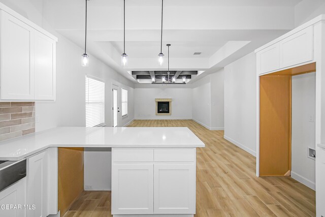 kitchen featuring light hardwood / wood-style flooring, kitchen peninsula, decorative light fixtures, and white cabinets