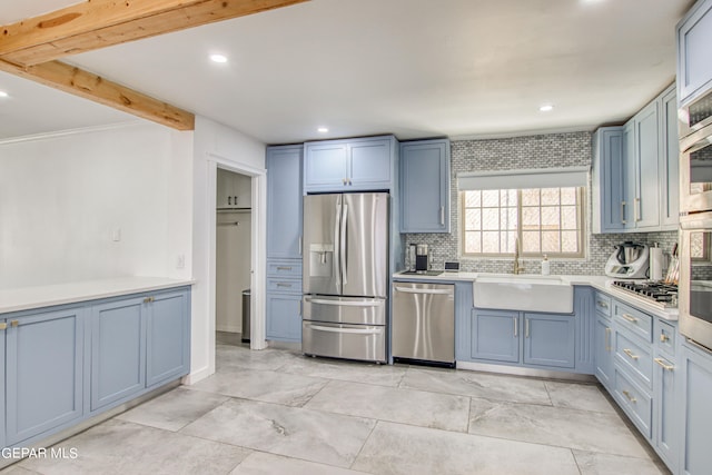 kitchen featuring blue cabinets, sink, appliances with stainless steel finishes, and decorative backsplash