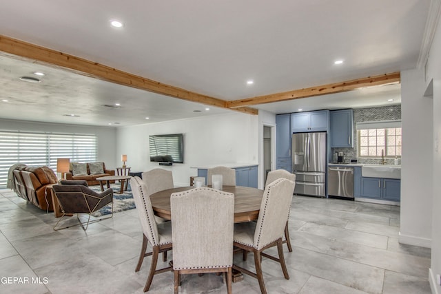 dining area with beam ceiling, a healthy amount of sunlight, and sink