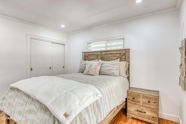 bedroom with a closet, ornamental molding, and hardwood / wood-style floors