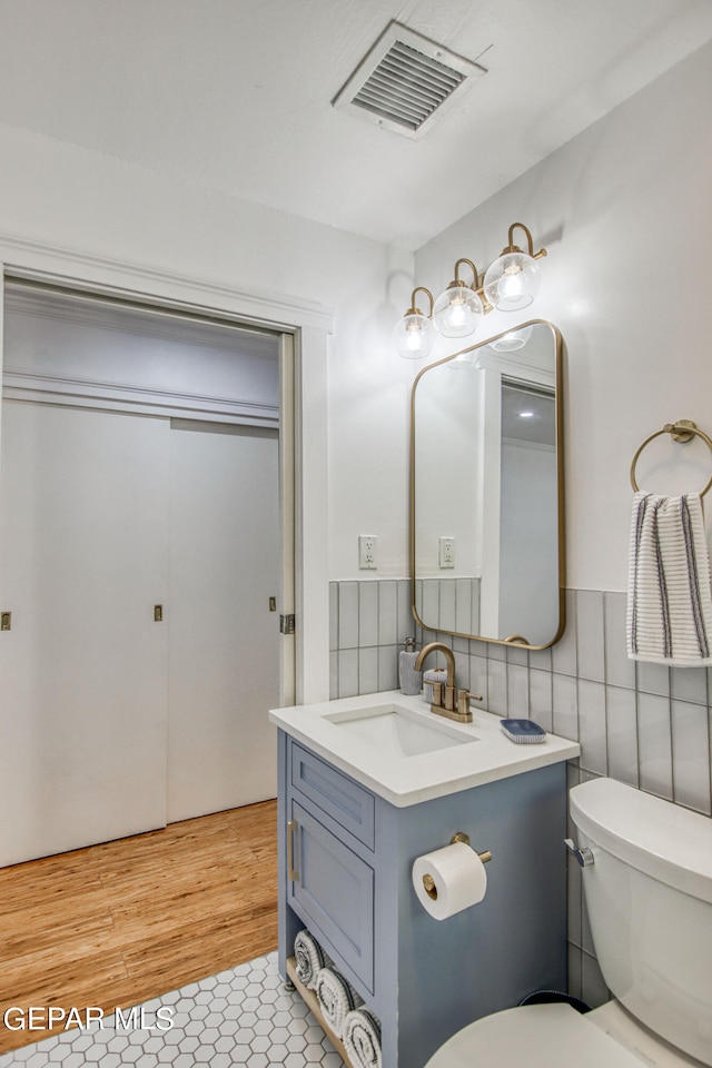 bathroom with vanity, tile patterned floors, toilet, and tile walls