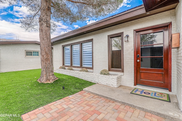 view of exterior entry with a lawn