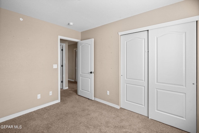 unfurnished bedroom featuring a closet and light colored carpet