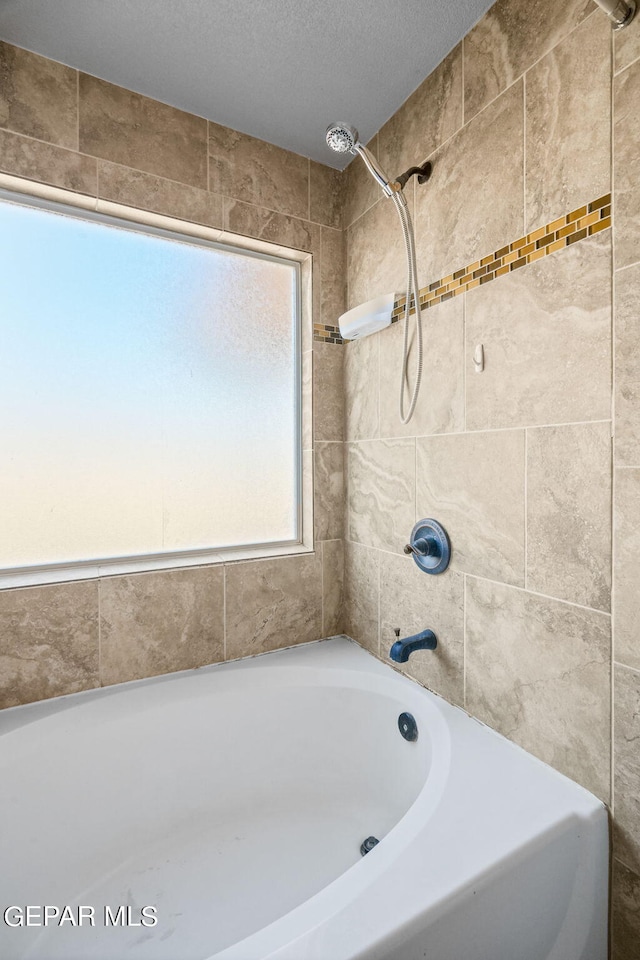 bathroom featuring tiled shower / bath and a textured ceiling