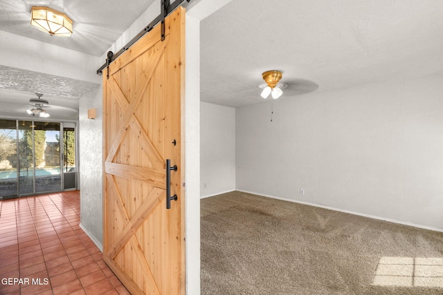 interior space featuring a textured ceiling, a barn door, carpet floors, and ceiling fan