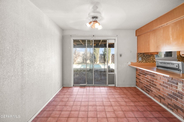 unfurnished dining area with a textured ceiling and ceiling fan