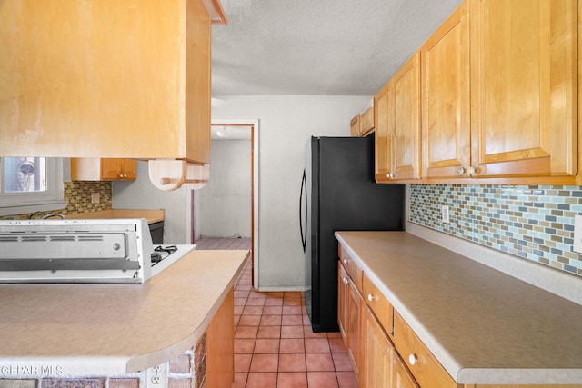kitchen with backsplash, a textured ceiling, kitchen peninsula, light tile patterned floors, and black refrigerator