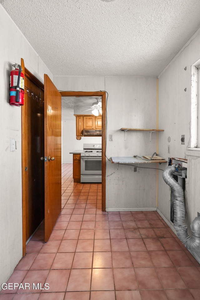 kitchen featuring white range with gas cooktop, a textured ceiling, and light tile patterned flooring