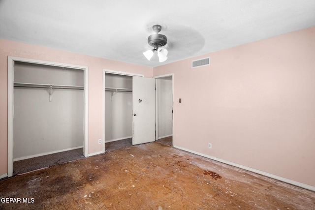 unfurnished bedroom featuring ceiling fan and two closets
