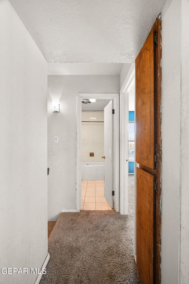 corridor featuring a textured ceiling and light colored carpet