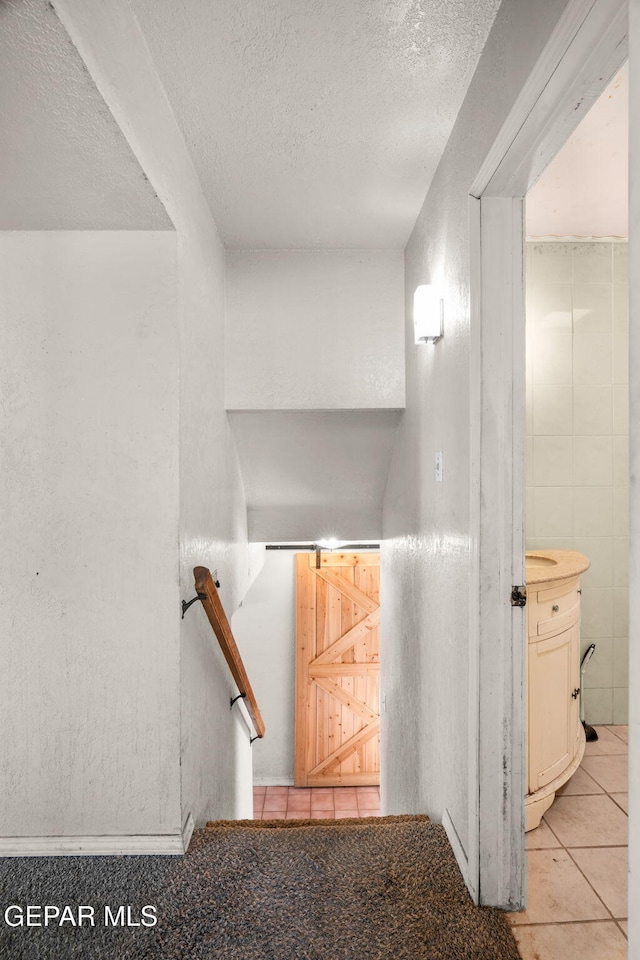 stairs with a textured ceiling, tile patterned floors, and tile walls