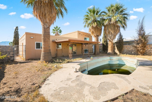 back of property featuring a patio and a fenced in pool