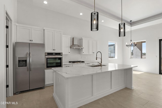 kitchen with white cabinets, hanging light fixtures, an island with sink, sink, and stainless steel appliances