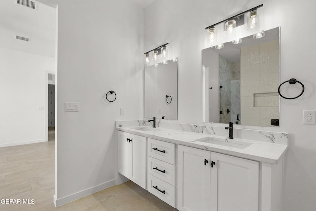 bathroom with a shower with door, vanity, and tile patterned flooring