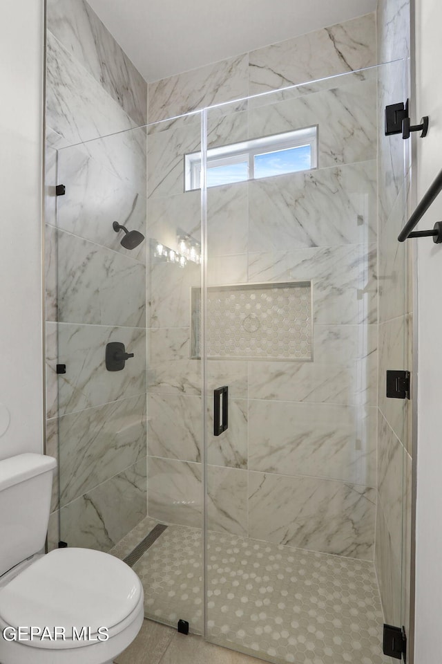 bathroom featuring toilet and a shower with shower door