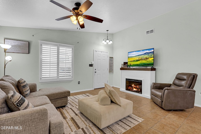 living room with ceiling fan with notable chandelier, lofted ceiling, and light tile patterned flooring