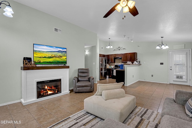 tiled living room featuring ceiling fan with notable chandelier and high vaulted ceiling