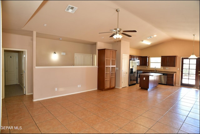 kitchen featuring a center island, lofted ceiling, sink, light tile patterned flooring, and stainless steel appliances