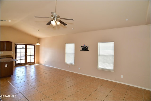 spare room featuring ceiling fan, a healthy amount of sunlight, lofted ceiling, and light tile patterned floors