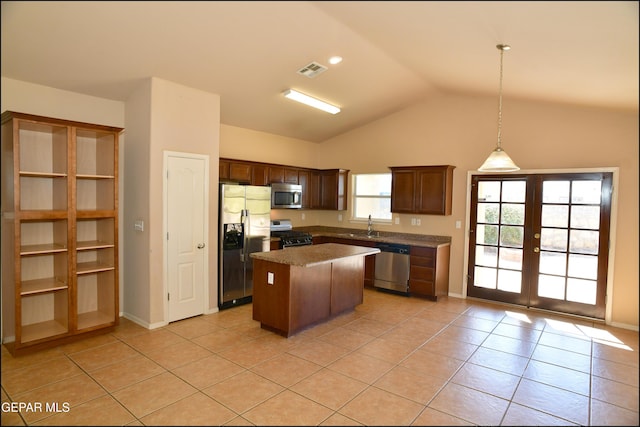 kitchen featuring a kitchen island, lofted ceiling, decorative light fixtures, light tile patterned floors, and appliances with stainless steel finishes