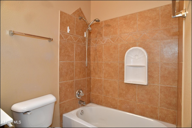 bathroom featuring tiled shower / bath combo and toilet