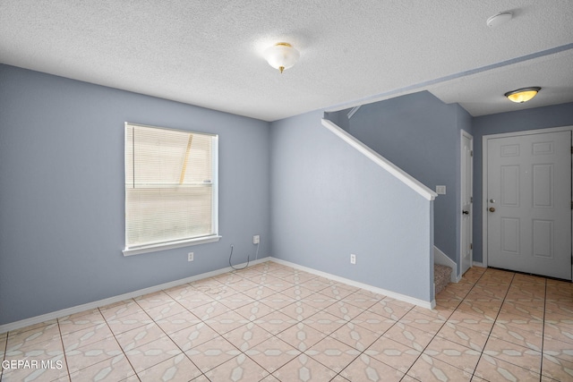 tiled spare room featuring a textured ceiling