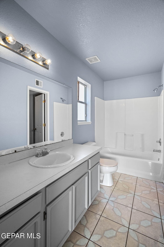 full bathroom featuring shower / washtub combination, a textured ceiling, toilet, vanity, and tile patterned flooring