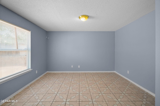 tiled empty room featuring a textured ceiling