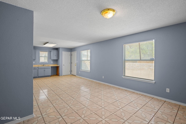 unfurnished living room featuring a textured ceiling, plenty of natural light, and light tile patterned floors