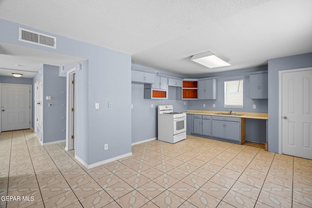 kitchen with white gas range oven, a textured ceiling, sink, and gray cabinets