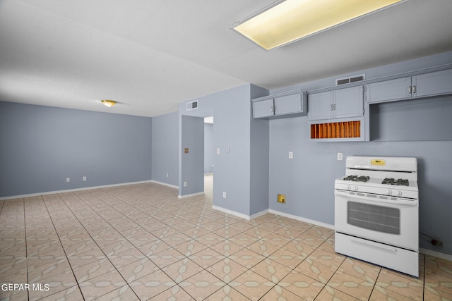 kitchen with gray cabinets, light tile patterned flooring, and white gas range oven