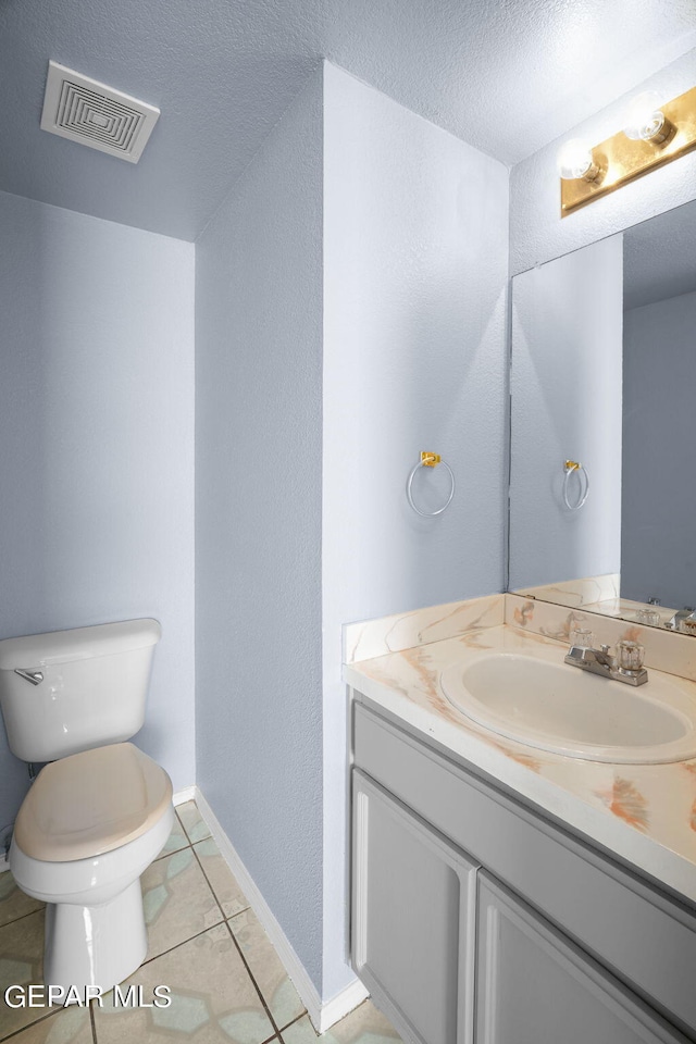 bathroom featuring vanity, toilet, a textured ceiling, and tile patterned flooring