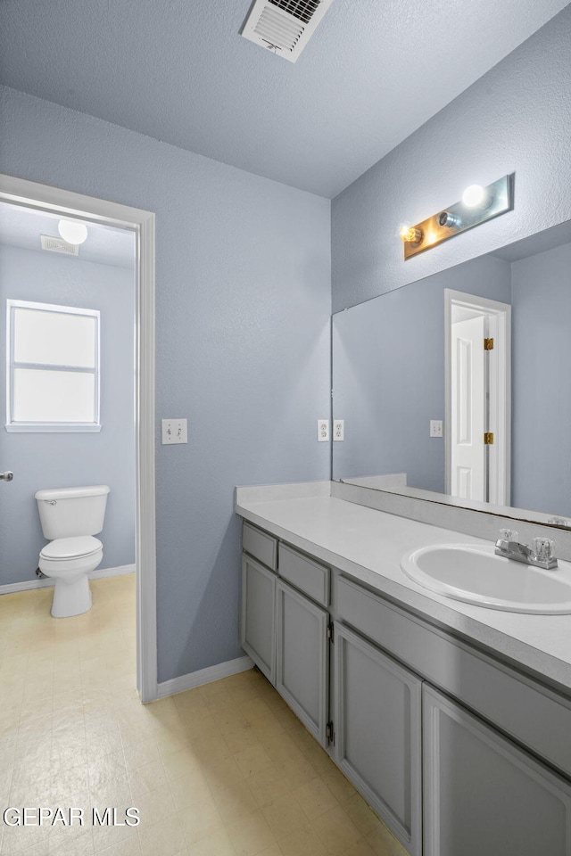 bathroom with vanity, toilet, and a textured ceiling