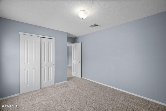 unfurnished bedroom with a closet, a textured ceiling, and carpet floors