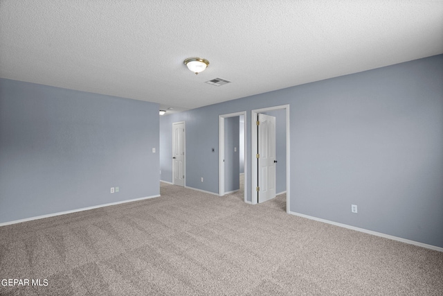 empty room featuring light carpet and a textured ceiling