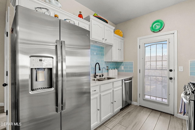 kitchen with appliances with stainless steel finishes, decorative backsplash, white cabinetry, and sink