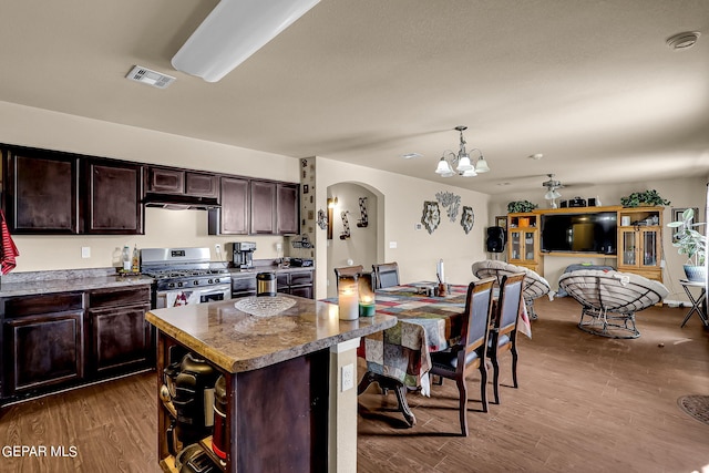 kitchen with a center island, wood-type flooring, stainless steel gas range, and dark brown cabinets