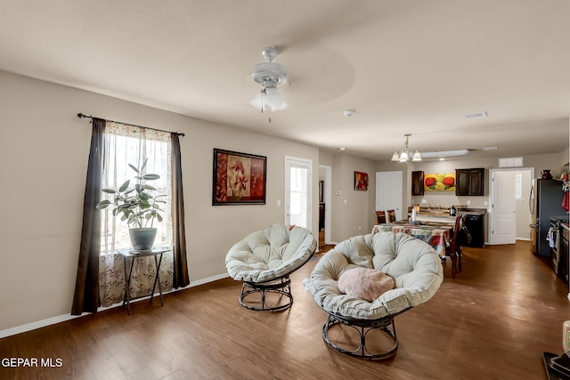 living room featuring dark hardwood / wood-style floors and ceiling fan with notable chandelier