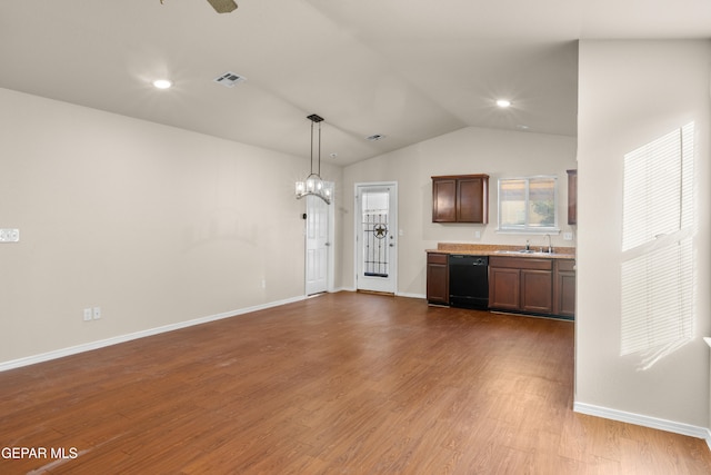 kitchen featuring black dishwasher, wood-type flooring, sink, and vaulted ceiling